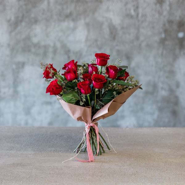Bouquet of red roses wrapped in brown paper with a striped ribbon
