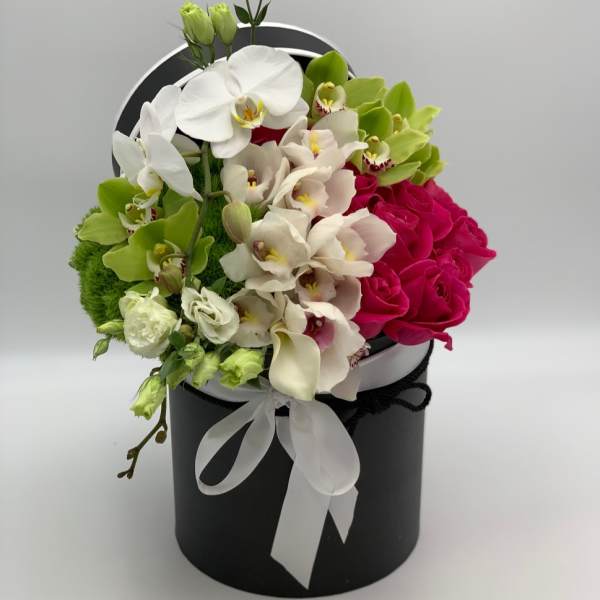 White and green orchids with hot pink roses in a black hat box