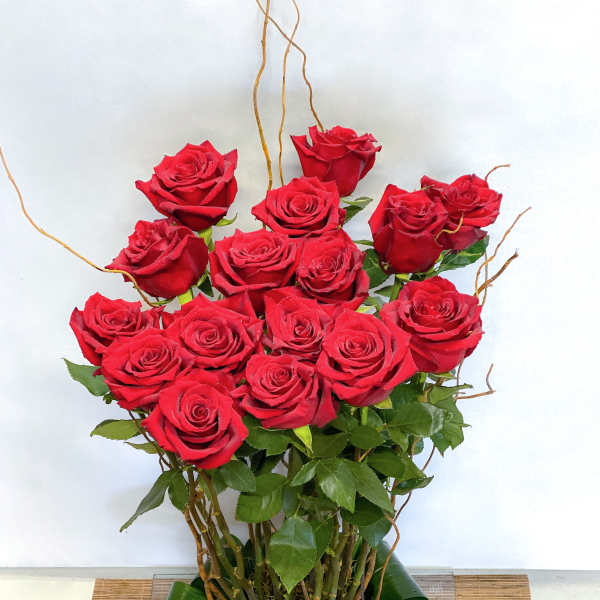 Tall bouquet of red roses with green leaves and decorative twigs