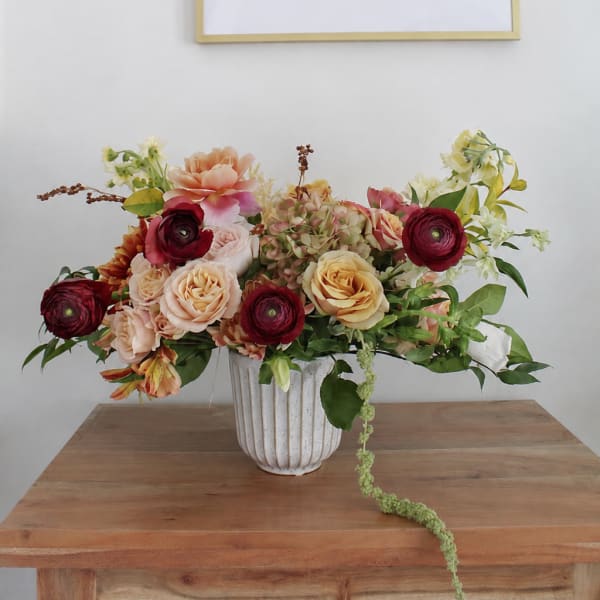 Mixed floral arrangement in a white vase on a wooden table