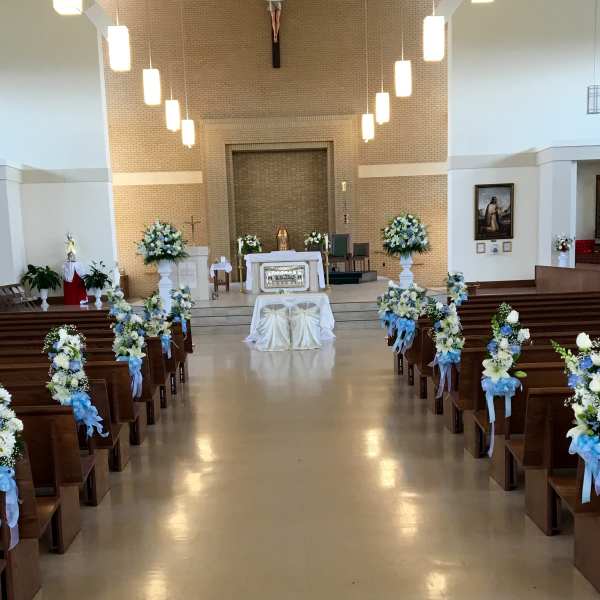 Church aisle decorated with blue and white floral arrangements for a ceremony