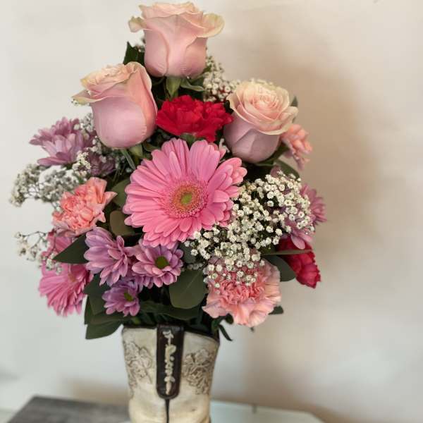 Pink roses and mixed flowers arranged in a cowboy boot vase