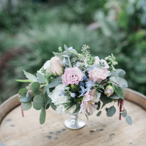 Small pastel floral arrangement in a silver pedestal vase
