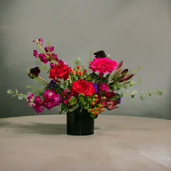 Red roses and pink gerbera daisies in a black vase