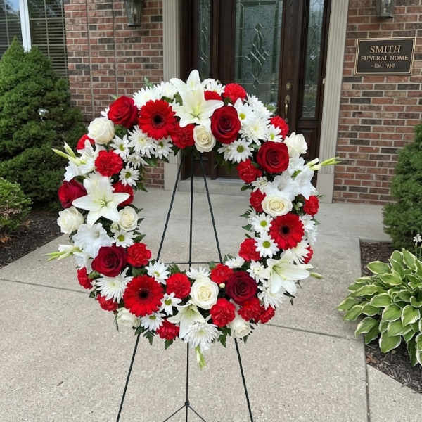 Red, white, and pink floral wreath on a stand outside a funeral home