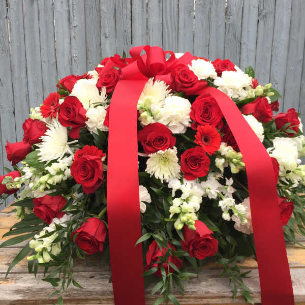 Red roses and white flowers arranged with a large red ribbon