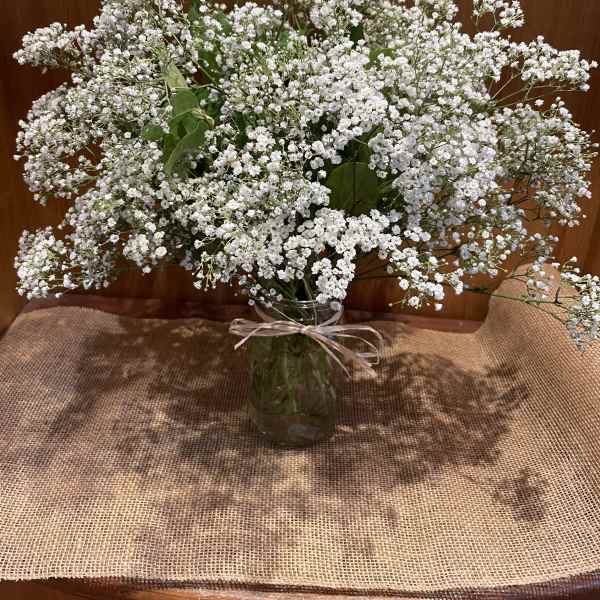 White baby's breath bouquet in a glass vase with a ribbon