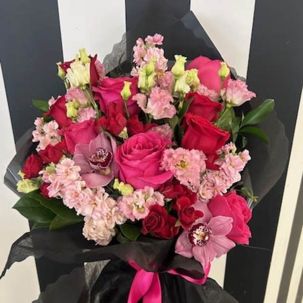 Bouquet of pink and red roses with orchids wrapped in black paper
