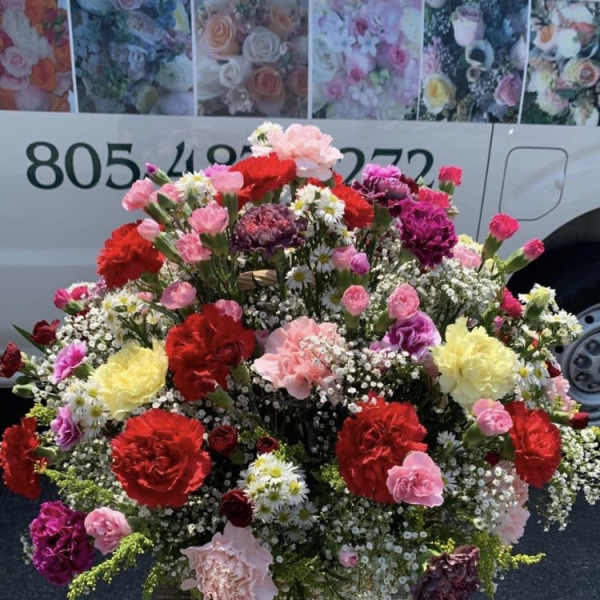 Large mixed flower arrangement in a basket on a stand