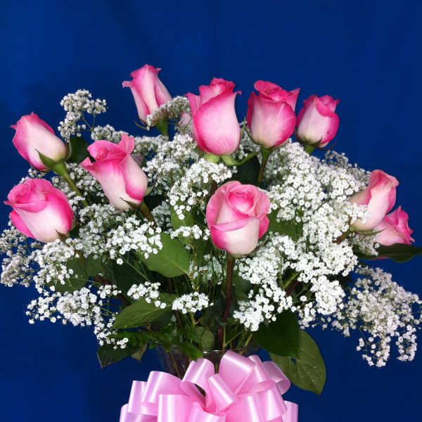 Pink roses with white baby's breath in a glass vase and pink bow