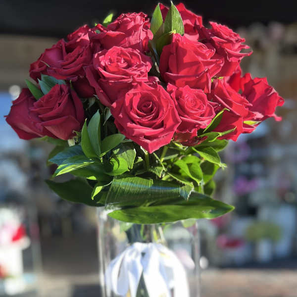 Bouquet of red roses in a clear glass vase with a white ribbon