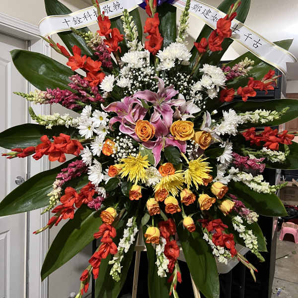 Large standing floral spray with red, white, yellow, and pink flowers