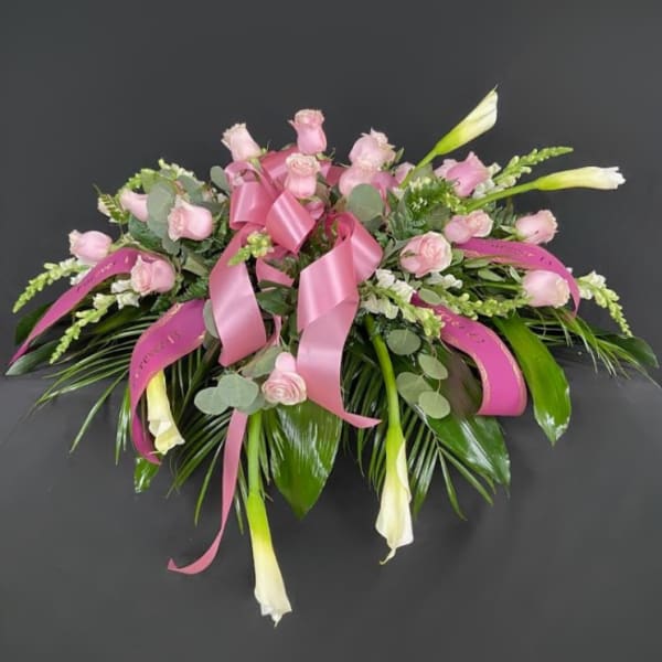 Pink rose bouquet with white calla lilies and ribbon on a dark background