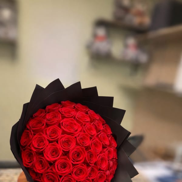 Round bouquet of red roses wrapped in black paper