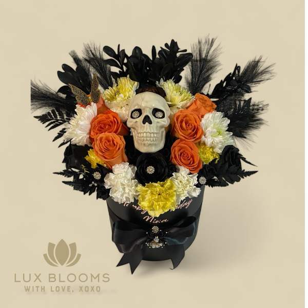 Black floral arrangement with a skull centerpiece and orange, white, and yellow flowers