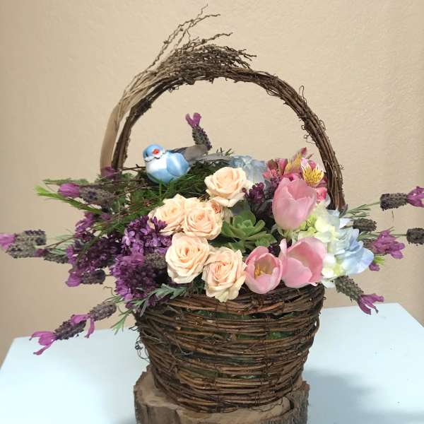 Basket arrangement with pink roses, tulips, and purple flowers