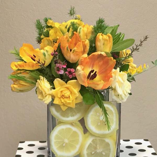 Yellow and orange tulips in a glass vase filled with lemon slices