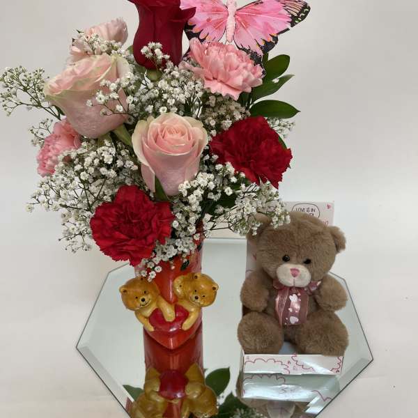 Pink and red flower arrangement with a teddy bear and butterfly