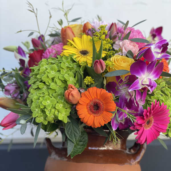 Colorful mixed bouquet in a terracotta vase with gerbera daisies and orchids