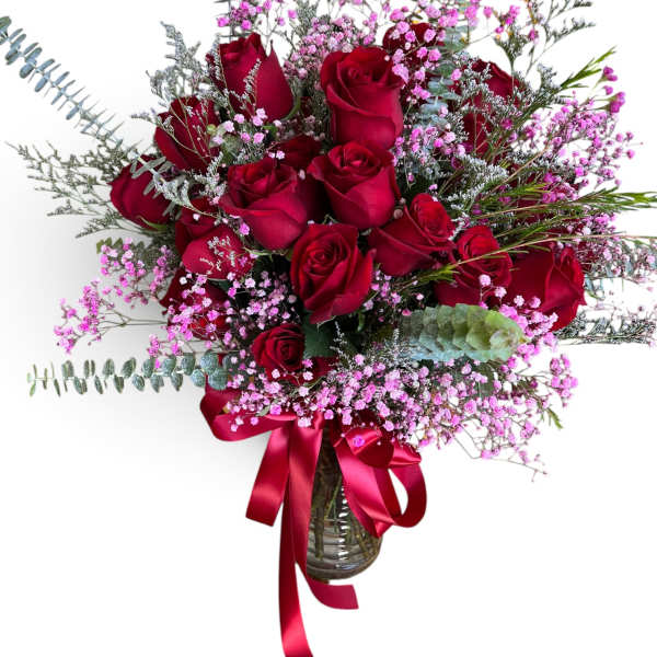 Red roses in a glass vase with pink filler flowers and a red ribbon