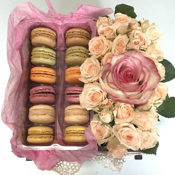 Macaron gift box beside a bouquet of pale pink roses