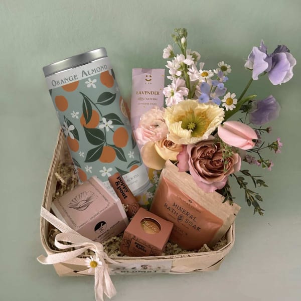 Gift basket with flowers, bath items, and a ribbon bow