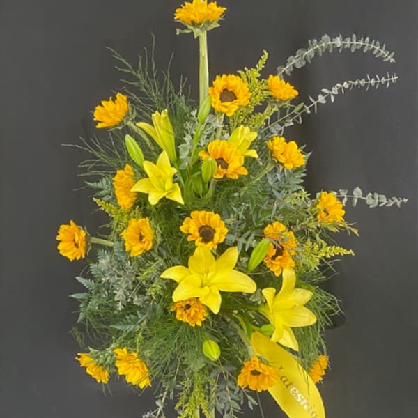Tall yellow floral spray with lilies and daisy-like blooms on a stand