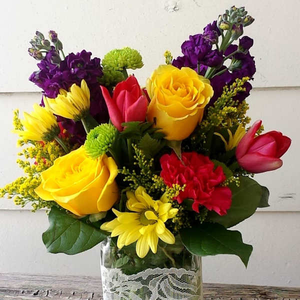 Colorful bouquet of roses, tulips, and daisies in a glass vase
