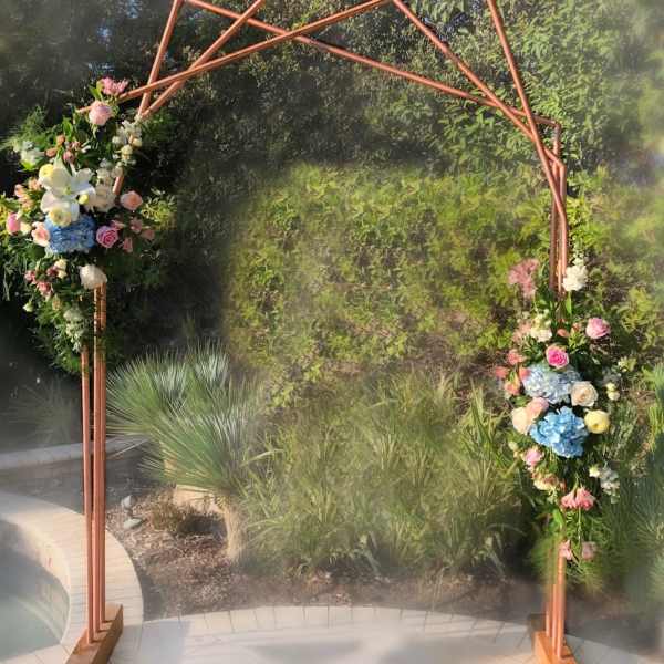 Floral arch with pink, white, and blue flowers on a copper frame