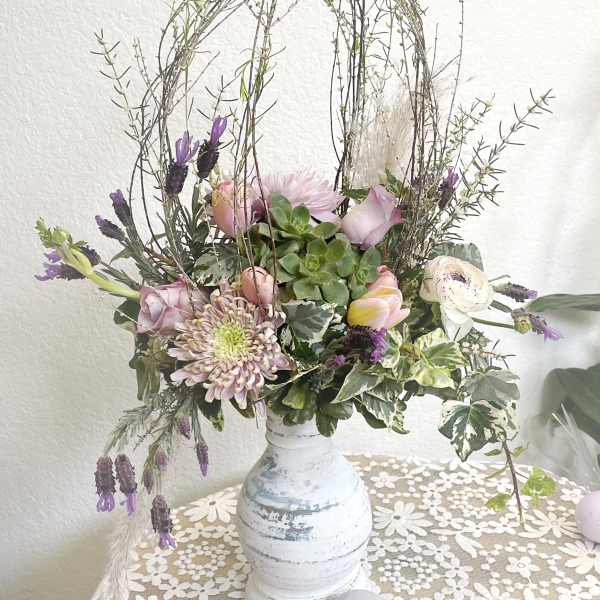 Pastel floral arrangement in a white vase with tall twig accents