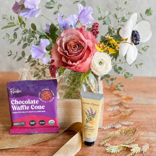 Bouquet in a glass vase with a chocolate bar and hand cream