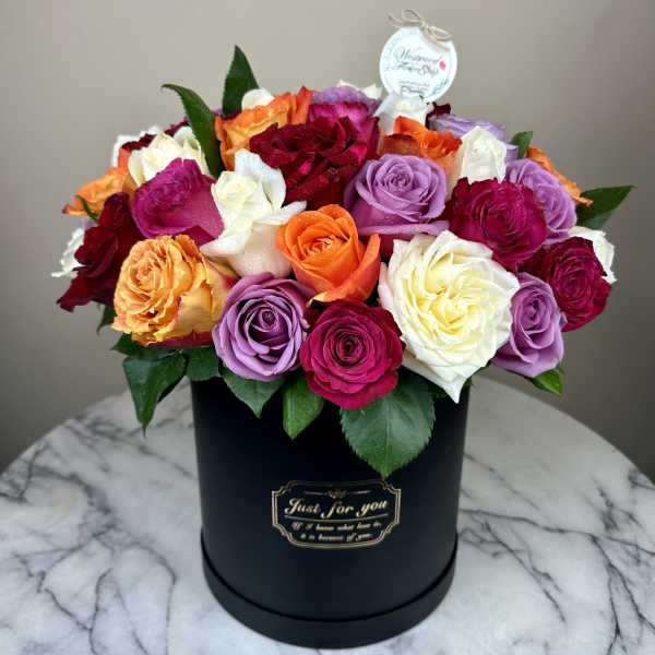 Colorful roses arranged in a black round box