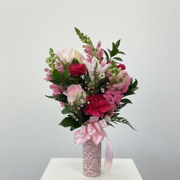 Pink and white mixed bouquet in a patterned vase with a pink ribbon