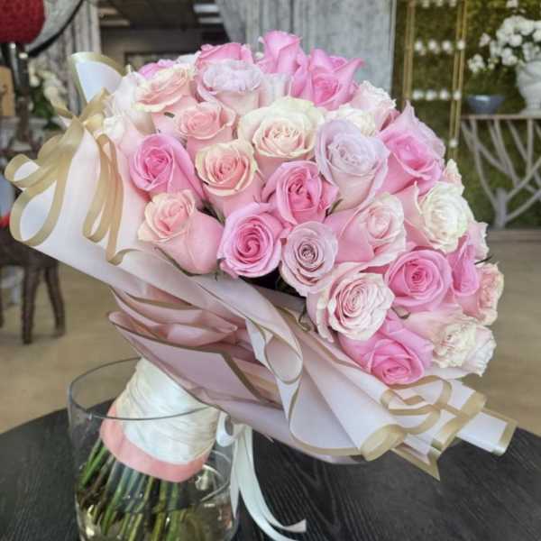 Bouquet of pink and white roses wrapped in pastel paper with ribbon