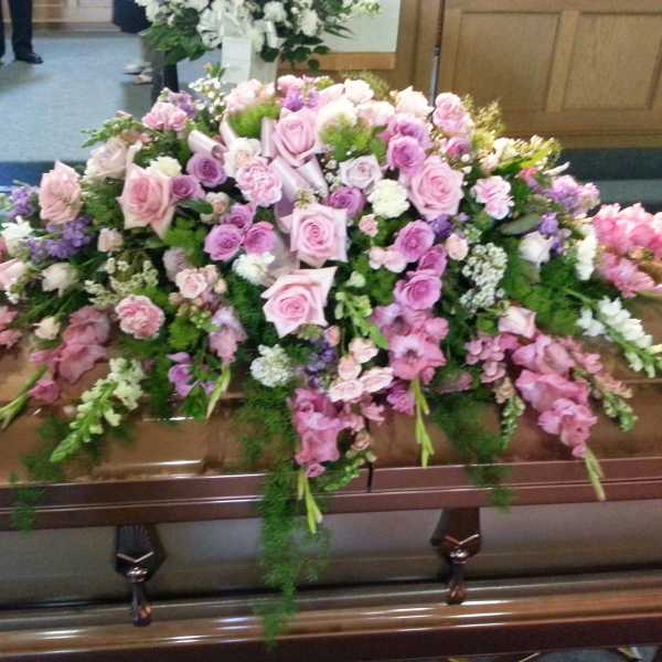 Large pink and white floral casket spray on a coffin