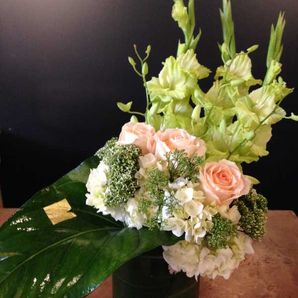 Arrangement of peach roses and white flowers in a black vase
