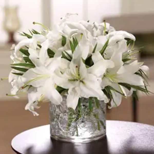 White lilies arranged in a clear glass vase