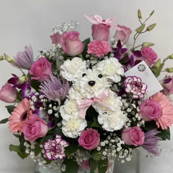 Pink and white flower arrangement with a teddy bear in a mirrored vase