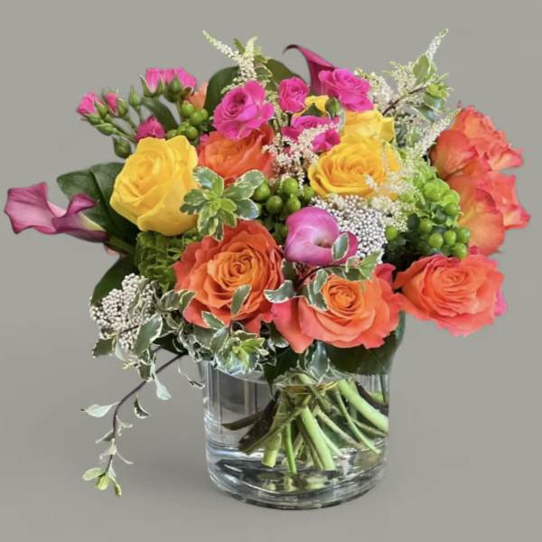 Colorful bouquet of roses and calla lilies in a glass vase