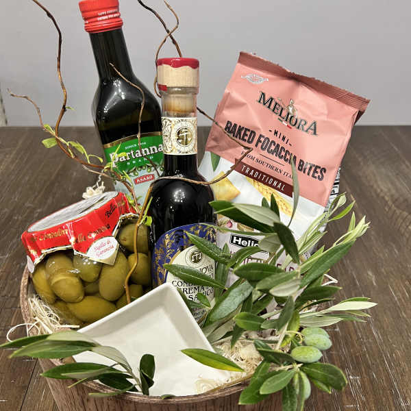 Gift basket with olive oil, olives, crackers, and a small dish