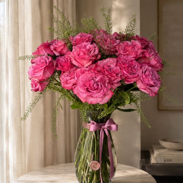Pink roses arranged in a clear glass vase with a ribbon