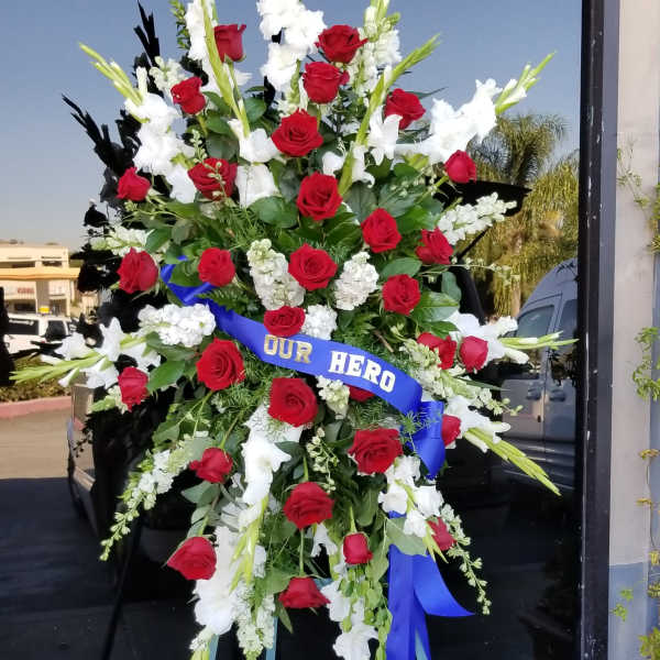 Large standing spray of red roses and white gladiolus with a blue ribbon