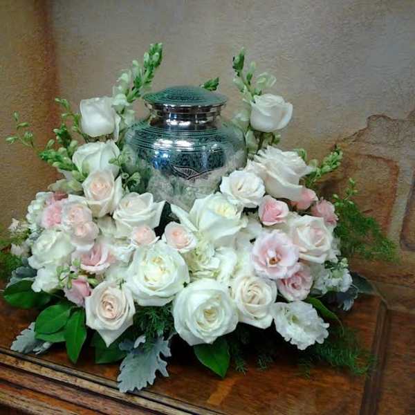 White and blush roses arranged around a silver urn