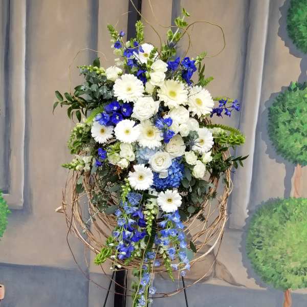 Tall floral spray with white and blue flowers in a twig frame