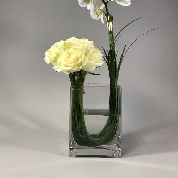 White orchid and pale yellow rose arrangement in a clear glass vase