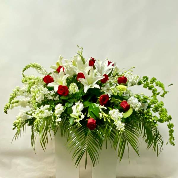 White lilies and red roses in a large arrangement with palm fronds