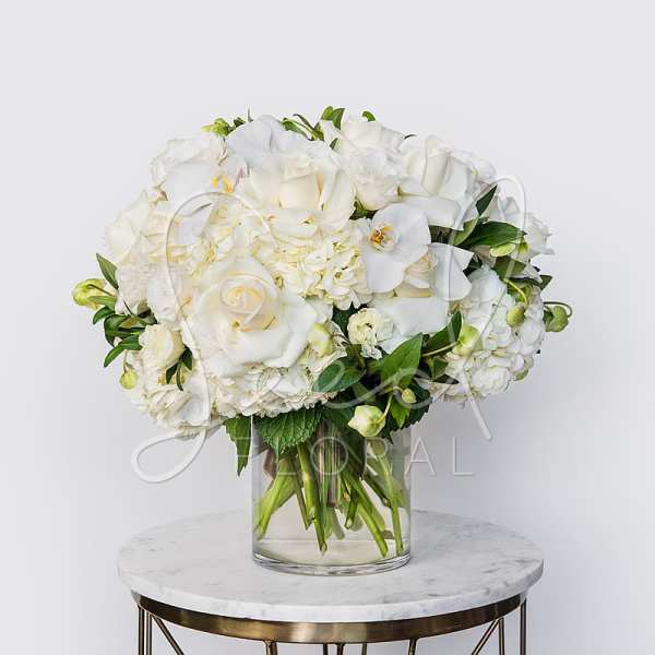 White roses and orchids arranged in a clear glass vase
