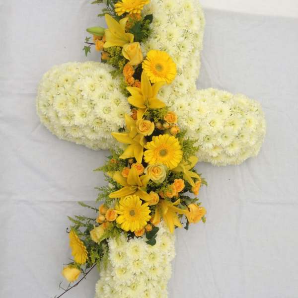 Cross-shaped floral arrangement with white chrysanthemums and yellow lilies and daisies