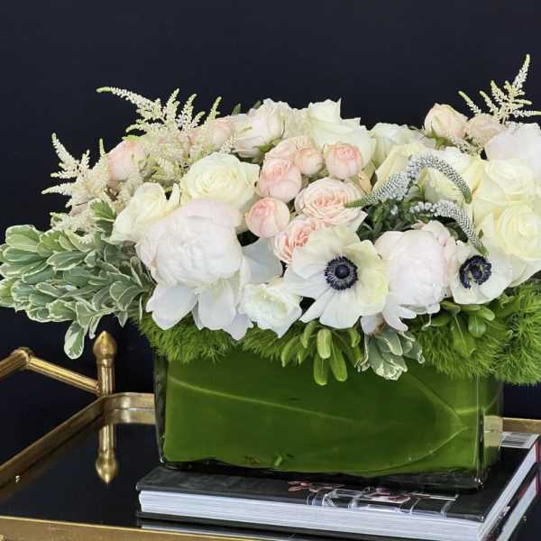 White and blush floral arrangement in a green glass vase