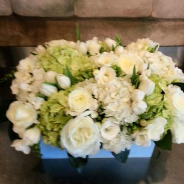 White floral arrangement in a square box with pale green blooms
